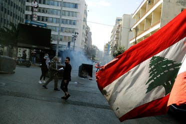 An anti-government demonstrator waves the national flag as they block the street, with burning garbage dumpsters, in front of Lebanon's central bank in the capital Beirut on March 16, 2021. (File photo: AFP)