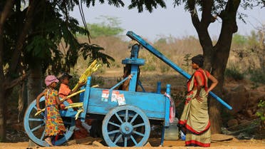 Indian children help a woman to extract juice from sugarcane as she sells them by a roadside on the outskirts of Hyderabad, India, Tuesday, March 16, 2021. (File photo: AP)