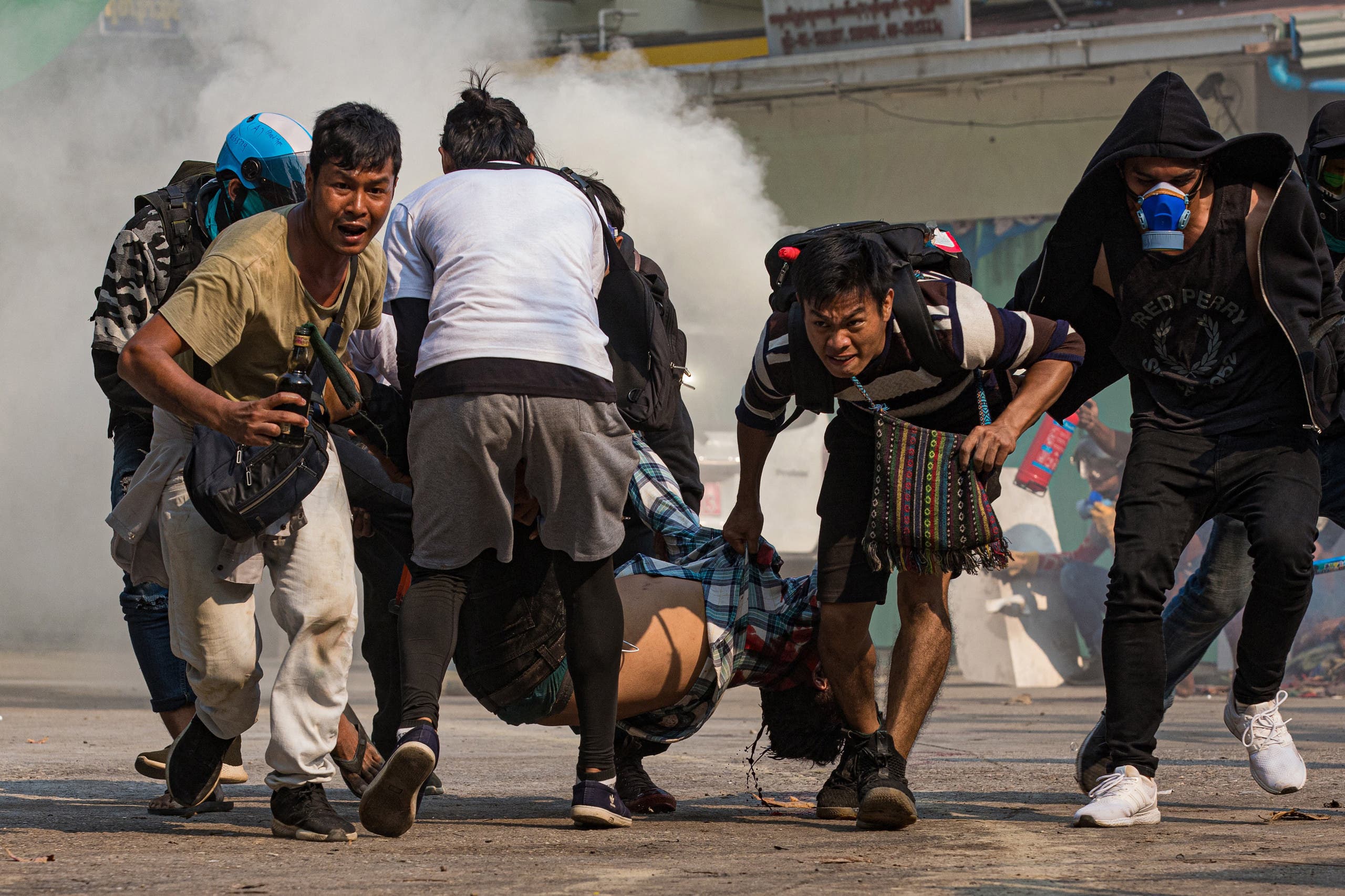Protesters carry a wounded man shot with live rounds by security forces during a crackdown on demonstrations against the military coup in Yangon on March 17, 2021 (File photo: AFP).