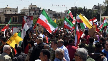 Syrians wave the Russian and Iranian flags and carry portraits of President Bashar al-Assad as they gather in Aleppo's Saadallah al-Jabiri square on April 14, 2018, to condemn the strikes carried out by the United States, Britain and France against the Syrian regime.
