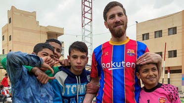 Islam Mohammed Ibrahim Battah, an Egyptian with a striking resemblance to Barcelona’s forward Lionel Messi, poses for a photograph with boys, Cairo, March 23, 2021. (Reuters)