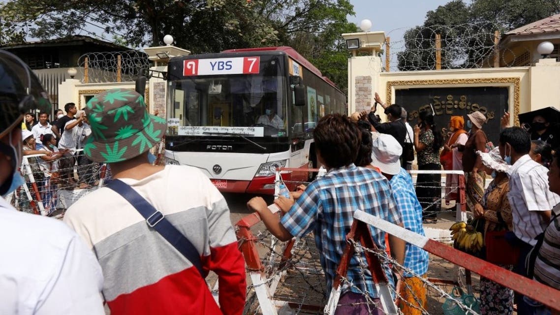 Onlookers watch as a bus ferrying coup detainees is driven out from Insein prison in Yangon on March 24, 2021, where they had been held for taking part in demonstrations against the military coup. (AFP)
