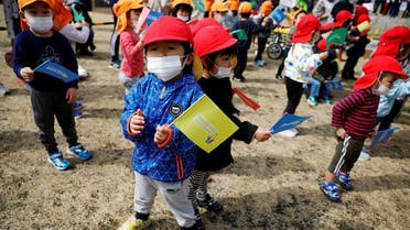 Children wearing face masks wait along the route of the Tokyo 2020 Olympic torch relay, amid the coronavirus disease (COVID-19) pandemic, on the first day of the relay in Naraha, Fukushima prefecture, Japan . (Reuters)