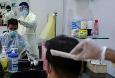 A barber wears a protective face shield and gloves as he cuts hair of a customer at a local barber shop in Riyadh. (File photo: Reuters)