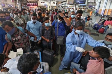 A healthcare worker collects a swab sample from a passenger as others wait for their turn upon arrival at a railway station during a rapid antigen testing campaign for the coronavirus disease (COVID-19) in Mumbai, India, March 25, 2021. (File photo: Reuetrs)