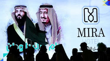People walk past a poster of Saudi Arabia's King Salman bin Abdulaziz Al Saud and Crown Prince Mohammed bin Salman as they celebrate Saudi Arabia's 90th annual National Day. (Reuters)