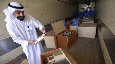 Employee at the Kuwaiti Information Ministry Essam al-Said inspects boxes in the back of a truck containing Kuwaiti archives seized during the Iraqi invasion of the Gulf emirate in 1990, after their restitution by Iraqi authorities in Kuwait City, on March 28, 2021. (Yasser Al-Zayyat/AFP)