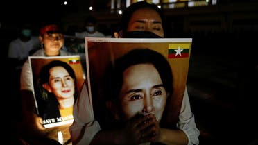 Migrants protesting against the military junta in Myanmar hold pictures of leader Aung San Suu Kyi, during a candlelight vigil at a Buddhist temple in Bangkok, Thailand, March 28, 2021. (Reuters)