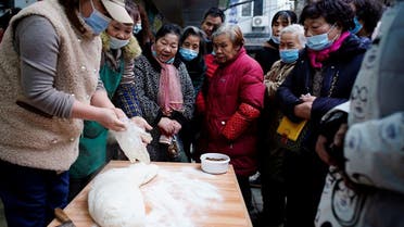 People wait to buy food at a street market almost a year after the start of the coronavirus disease outbreak, in Wuhan, China Dec. 7, 2020. (Reuters)