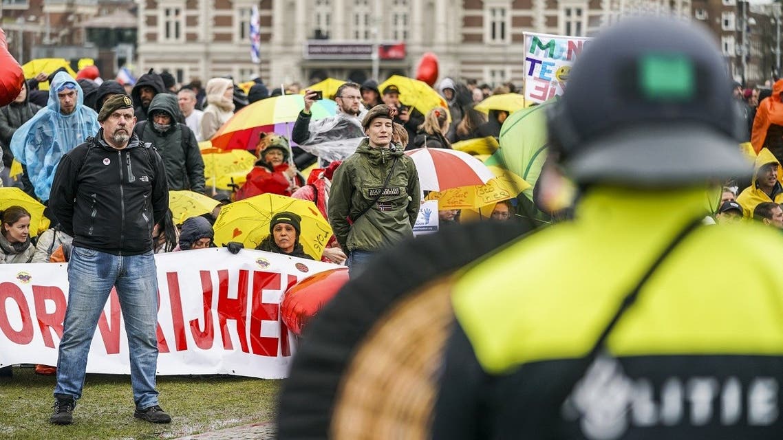 Dutch riot police watch campaigners in military clothing as they gather with protesters on the Museumplein for the so-called Coffee Drink campaign to denounce the government’s handling of the COVID-19 pandemic, in Amsterdam on March 28, 2021. (Jeroen Jumelet/ANP/AFP)