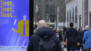 People walk past an ad promoting free coronavirus tests at Berlin’s Kurfuerstendamm street on March 29, 2021, amid the novel coronavirus pandemic. (AFP)