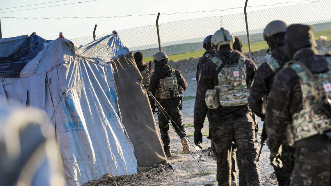 An image grab from a video made available on the People's Protection Units' (YPG) Press office on March 28, 2021, shows Kurdish YPG forces lining-up men by a fence during a security operation at the Kurdish-run Al-Hol camp which holds suspected relatives of Islamic State (IS) group fighters, in the northeastern Syrian Hasakeh governorate. Kurdish forces made dozens of arrests in a security operation launched at the camp for suspected family members of Islamic State group militants in northeast Syria, a war monitor and Kurdish officials said. Al-Hol is the largest such settlement controlled by Kurdish authorities, who warn it is emerging as an extremist powder keg following dozens of murders in the camp since the start of the year.