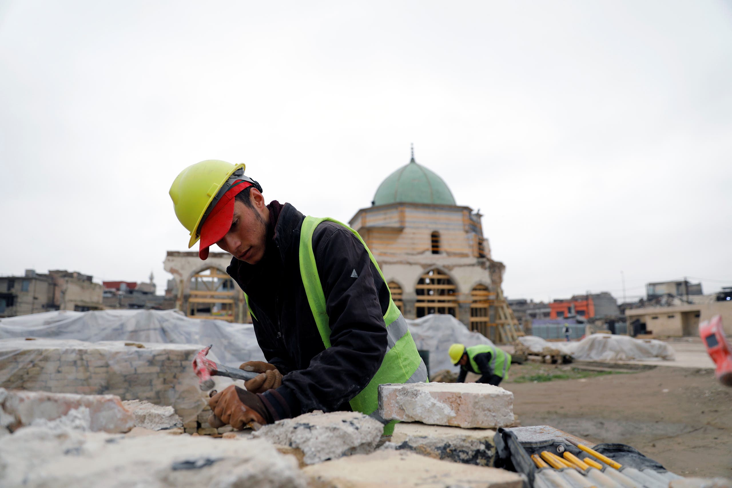 A laborer cleans a rock during the re-construction of the Grand al-Nuri mosque, in the old city of Mosul, Iraq January 23, 2020. Picture taken January 23, 2020. (Reuters)