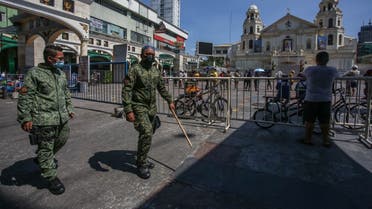 Police officers patrol as Roman Catholic devotees gather in front of Quiapo church during Good Friday in Manila on April 2, 2021, after the government imposed strict lockdowns to cope with a surge in COVID-19 infections. (Jam Sta Rosa/AFP)