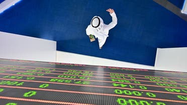 A trader walks by beneath a stock display board at the Dubai Stock Exchange in the United Arab Emirates, on March 8, 2020. (AFP)