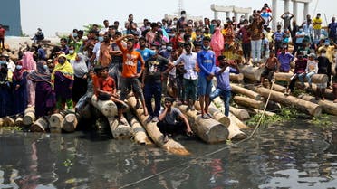 Relatives and onlookers watch the rescue operation of a ferry that collided with a cargo vessel and sank on Sunday in the Shitalakhsyaa River, in Narayanganj, Bangladesh, April 5, 2021. (Reuters)