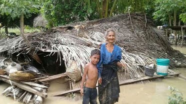 An elderly villager and her grandson stand in floodwaters in front of their damaged home in the village of Haitimuk in East Flores on April 4, 2021, after flash floods and landslides swept eastern Indonesia and neighbouring East Timor. (File photo: AFP)