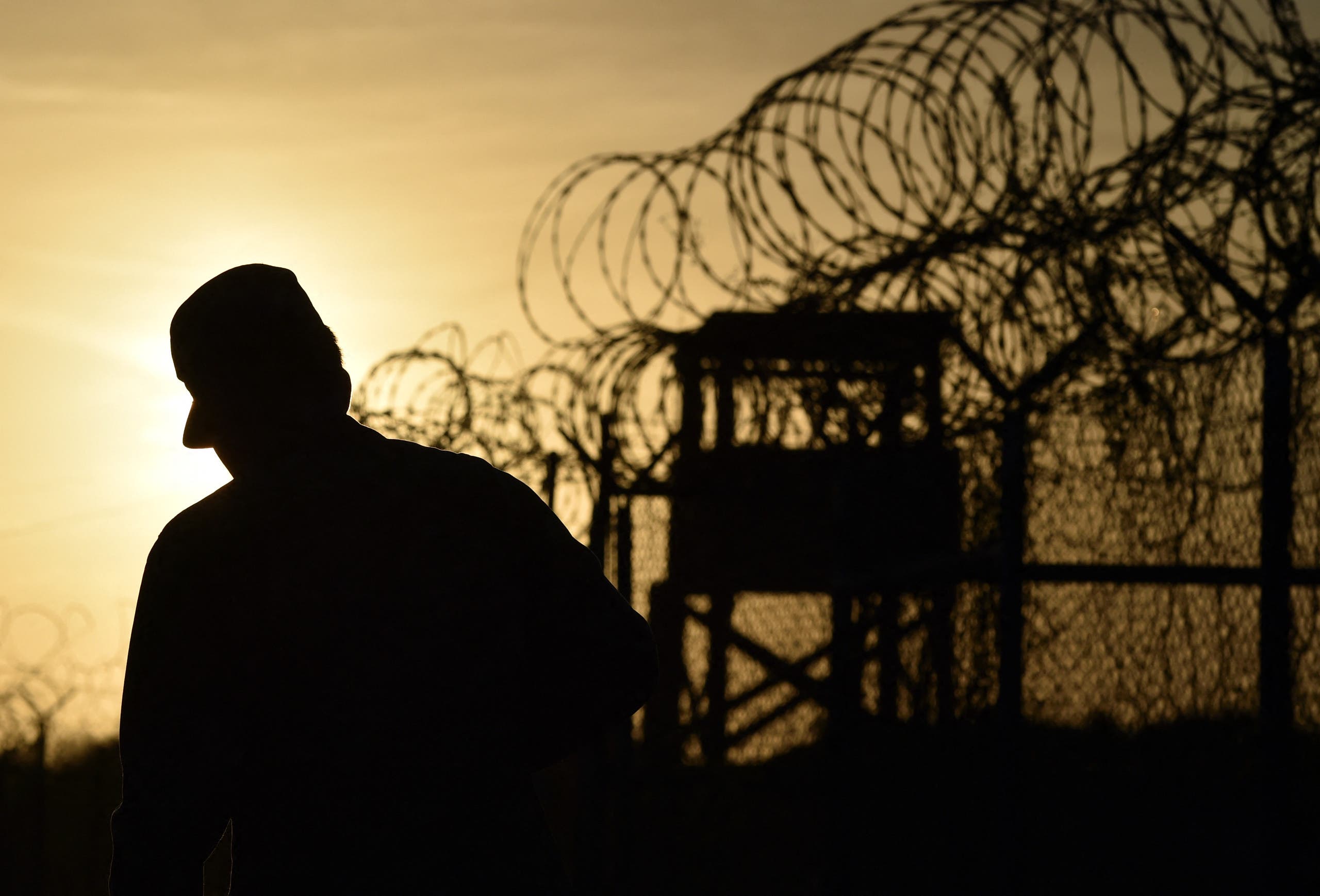 This photo made during an escorted visit and reviewed by the US military, shows an US soldier walking next to the razor wire-topped fence at the abandoned Camp X-Ray detention facility at the US Naval Station in Guantanamo Bay, Cuba, April 9, 2014. (AFP)