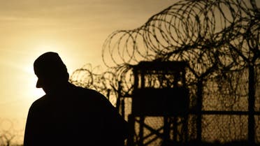 This photo made during an escorted visit and reviewed by the US military, shows an US soldier walking next to the razor wire-topped fence at the abandoned Camp X-Ray detention facility at the US Naval Station in Guantanamo Bay, Cuba, April 9, 2014. AFP PHOTO/MLADEN ANTONOV