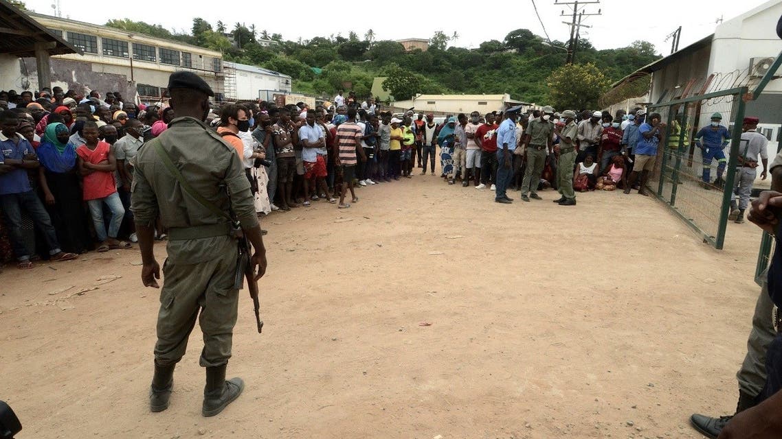 Security officials stand guard as people wait for friends and relatives as a ship carrying more than 1,000 people fleeing an attack claimed by Islamic State-linked insurgents on the town of Palma, docks in Pemba, Mozambique, on April 1, 2021. (Reuters)
