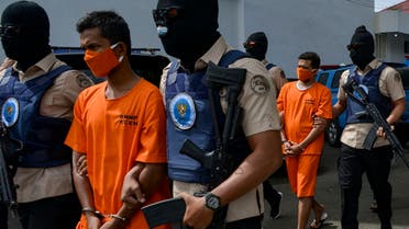 Indonesian National Narcotic Agency (BNN) officers escort two local men suspected of smuggling methamphetamine at a press conference in Banda Aceh on October 13, 2020. (AFP)