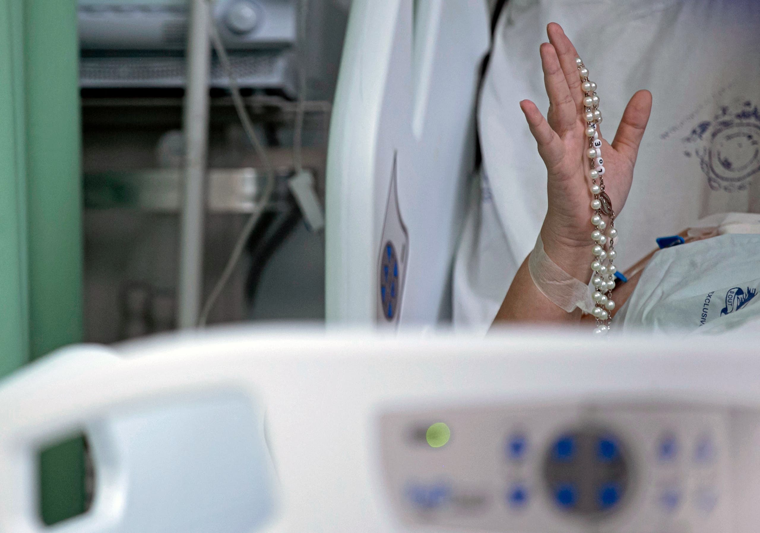 A COVID-19 patient holds up a rosary beads as health workers from the Portuguese charity hospital in Belem, state of Para, Brazil, sing and pray for COVID-19 patients inside the hospital wards and ICU areas as part of Easter celebrations on April 4, 2021. (File photo: AFP)
