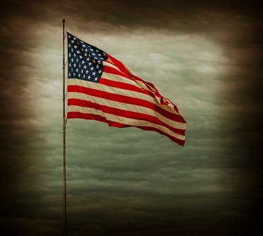 Flag of the United States of America against the background of black clouds before a hurricane. (Stock photo)