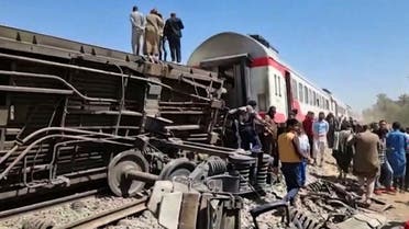 This screengrab provided by AFPTV shows people gathered around the wreckage of two trains that collided in the Sohag province, south of the Egyptian capital Cairo, on March 26, 2021. (AFP)