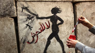 An Egyptian activist draws graffiti depicting a woman and reading in Arabic: No to Sexual Harassement on a wall outside the presidential palace in Cairo on December 14, 2012. (AFP)