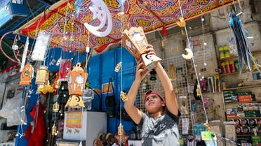 A Palestinian boy hangs a lantern as he sells products at a market, ahead of the holy fasting month of Ramadan, in Gaza City, on April 5, 2021. (Reuters)
