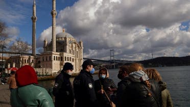 Turkish police officers check the passports of a group of Russian tourists at Ortakoy square during a nation-wide weekend curfew which was imposed to prevent the spread of the coronavirus disease (COVID-19) in Istanbul, Turkey February 28, 2021. (Reuters)