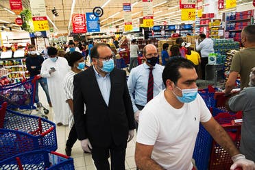 In this Sunday, April 19, 2020 photo, Majid Al Futtaim CEO Alain Bejjani, (center left), and store manager Arnaud Bouf (center), walk through heavy shopping traffic during the coronavirus pandemic in the world's busiest Carrefour supermarket, at the Mall of the Emirates in Dubai, UAE. (AP)