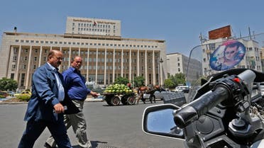 Men walk outside the Central Bank of Syria headquarters in the Sabaa Bahrat Square of the capital Damascus. (AFP)