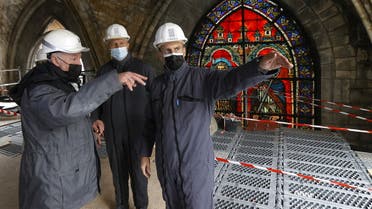 French President Emmanuel Macron speaks with a worker and the French Army General Jean-Louis Georgelin in front of a stained glass window under the damaged vaults during a visit at the reconstruction site of the Notre-Dame de Paris Cathedral, which was damaged in a devastating fire two years ago, as restoration works continue, in Paris, France, April 15, 2021. (Reuters)
