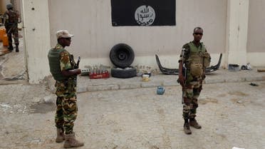 Chadian soldiers stand at a checkpoint in front of a Boko Haram flag the Nigerian city of Damasak, Nigeria. (AP)