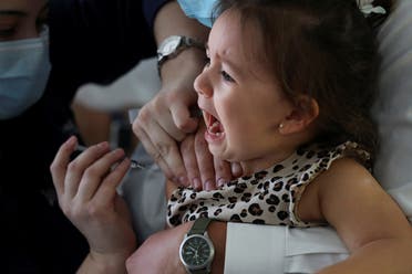 A child reacts while receiving a vaccine as part of the seasonal flu vaccination campaign for children and elderly people, during the coronavirus pandemic, in Santiago, Chile, on April 13, 2021. (Reuters)