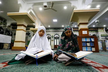 Women read the Quran as they wait to break the fast during the holy month of Ramadan, amid the coronavirus disease (COVID-19) pandemic, in Jakarta, Indonesia. (Reuters)