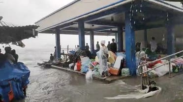 People stand in cover on a flooded market as Super Typhoon Surigae moves close to the Philippines in the province of Catbalogan, Samar, Philippines , onApril 18, 2021, in this screen grab obtained from a social media video. (Reuters)