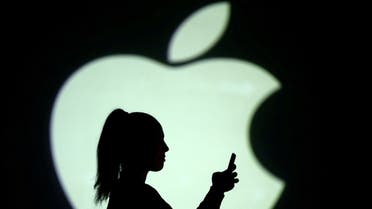 Silhouette of a mobile user seen next to a screen projection of the Apple logo in this picture illustration taken March 28, 2018. (Reuters)