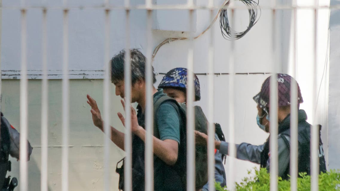 In this Feb. 26, 2021, photo, Japanese journalist Yuki Kitazumi raises his hands as he is escorted by police upon arrival at the Myaynigone police station in Sanchaung township in Yangon, Myanmar. (AP)