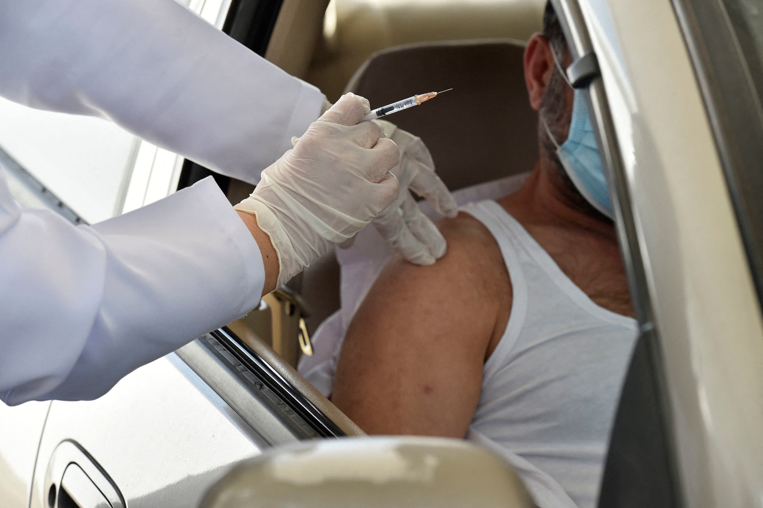 ممرضة تحقن رجلاً بجرعة من لقاح أسترازينيكا في مركز تطعيم في الرياض