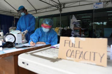 Health workers sort patients' files at a triage area in Santa Ana Hospital, where a sign indicating that the hospital's coronavirus disease (COVID-19) facility is at full capacity is displayed, in Manila, Philippines. (Reuters)