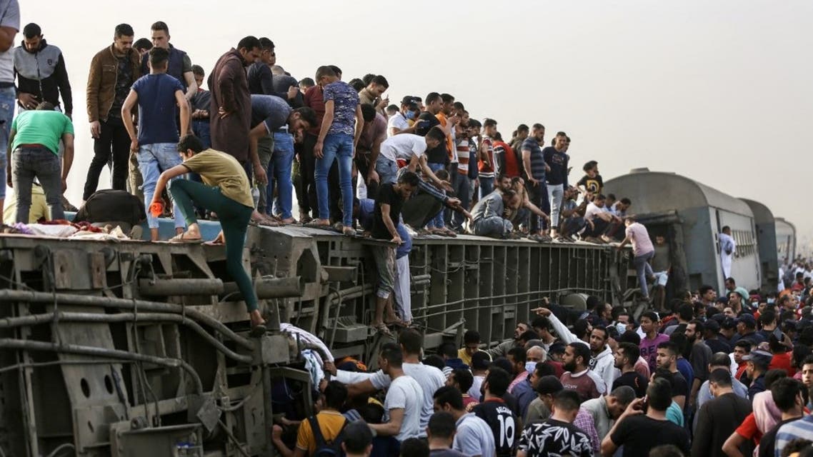 People climb an overturned train carriage as they gather at the scene of a railway accident in the city of Toukh in Egypt's central Nile Delta province of Qalyubiya on April 18, 2021. (AFP)