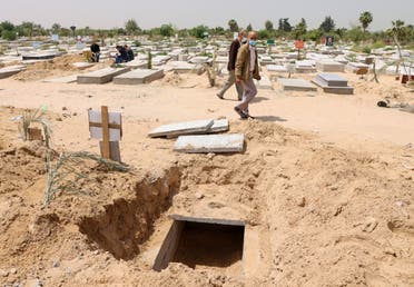 Palestinians walk past a grave dug for a coronavirus disease (COVID-19) victim, at a cemetery, east of Gaza City April 20, 2021. Picture taken April 20, 2021. (Reuters)