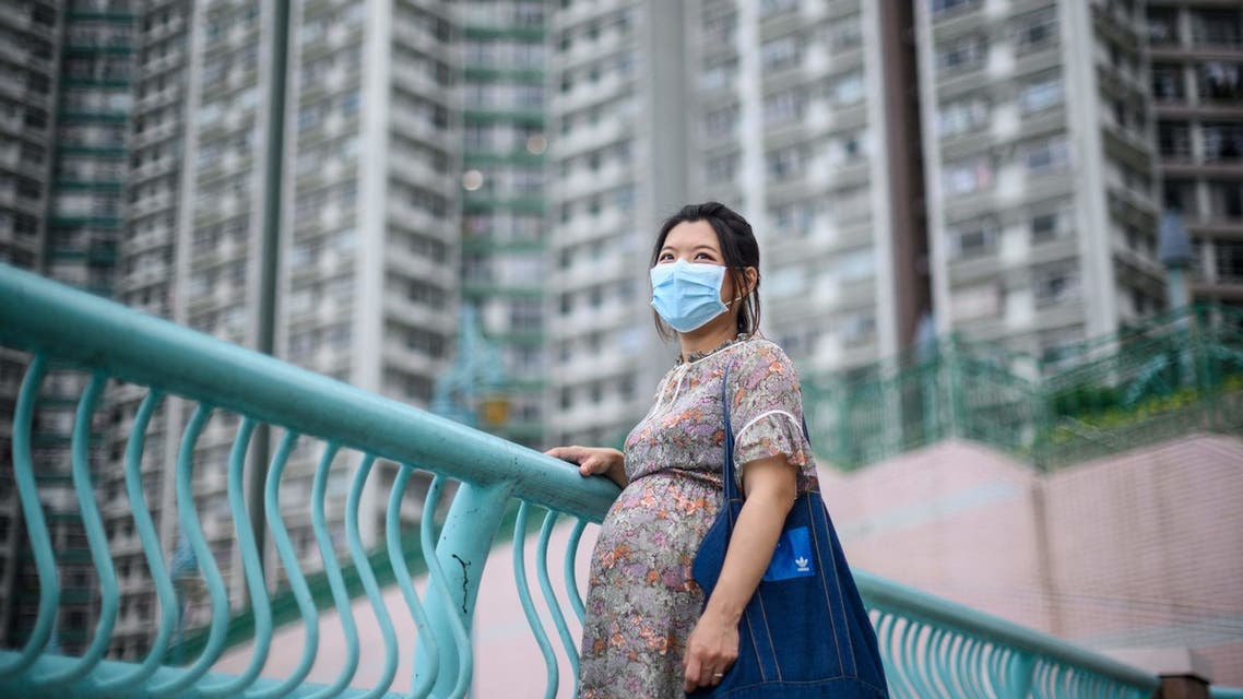 In this picture taken on March 31, 2020, expectant mother Jamie Chui, 33, poses in front of residential buildings near where she lives in Hong Kong. Jamie Chui has been a virtual prisoner in her Hong Kong home for most of her nine-month pregnancy. Trapped intially by violent pro-democracy protests and tear gas, and then by the coronavirus -- she now faces giving birth alone, with her husband unlikely to see his child until days later.