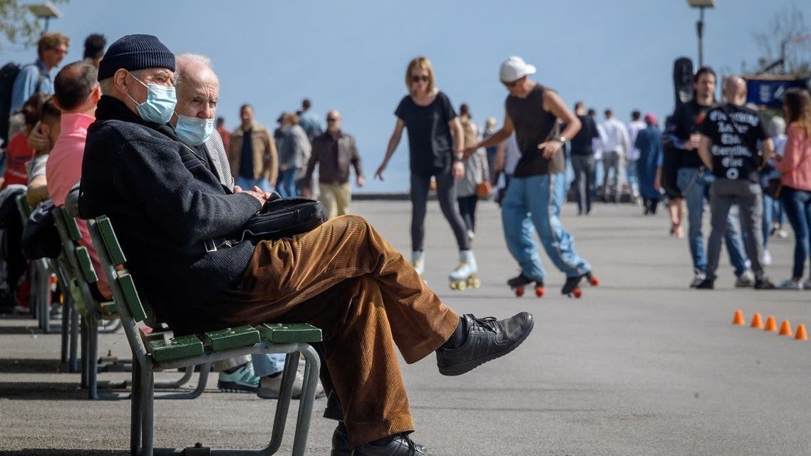 People wearing face masks enjoy a warm spring day on the edge of Lake Geneva in Lausanne on April 2, 2021, amid the COVID-19 pandemic. (Fabrice Coffrini/AFP)