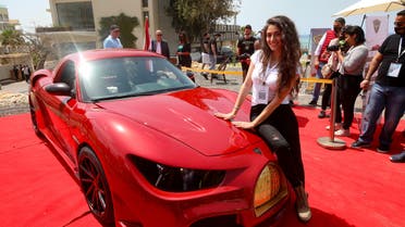 A model leans on the hood of the Quds Rise, the first ever electric car produced in Lebanon, during an unveiling ceremony in Khaldeh, south of the capital Beirut, on April 24, 2021. The front golden grille represents Al-Aqsa mosque's Dome of the Rock in Jerusalem. The lebanese-made electric car made its debut in a double first for the Mediterranean country that has never manufactured automobiles and is wracked by economic crisis and power cuts. (AFP)