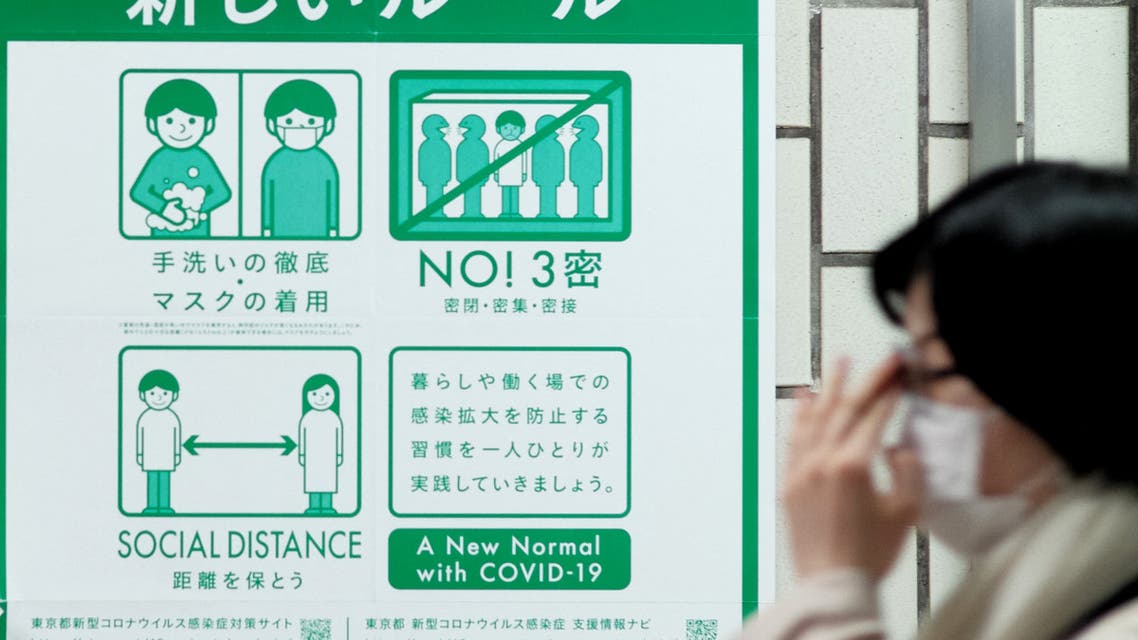 A woman walks past a public service display promoting social distancing at a subway station in Tokyo on April 26, 2021, during a new coronavirus state of emergency covering Tokyo, Osaka, Kyoto and Hyogo regions. (File photo: AFP)
