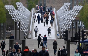 Pedestrians walk over the Millennium Bridge in the City of London on April 29, 2021. (AFP)