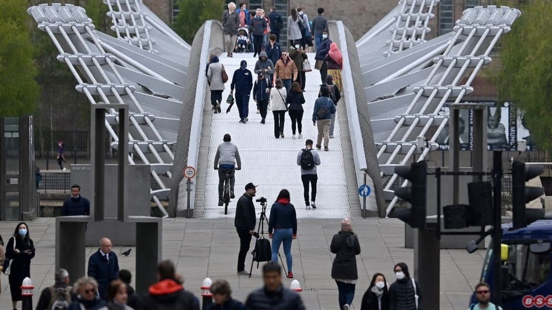 Pedestrians walk over the Millennium Bridge in the City of London on April 29, 2021. (AFP)